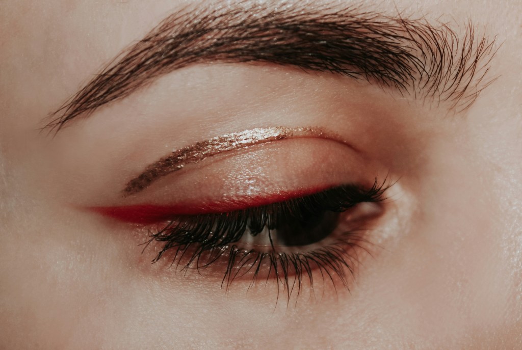 Close-up eye makeup with metallic liner and soft feathered eyebrows.