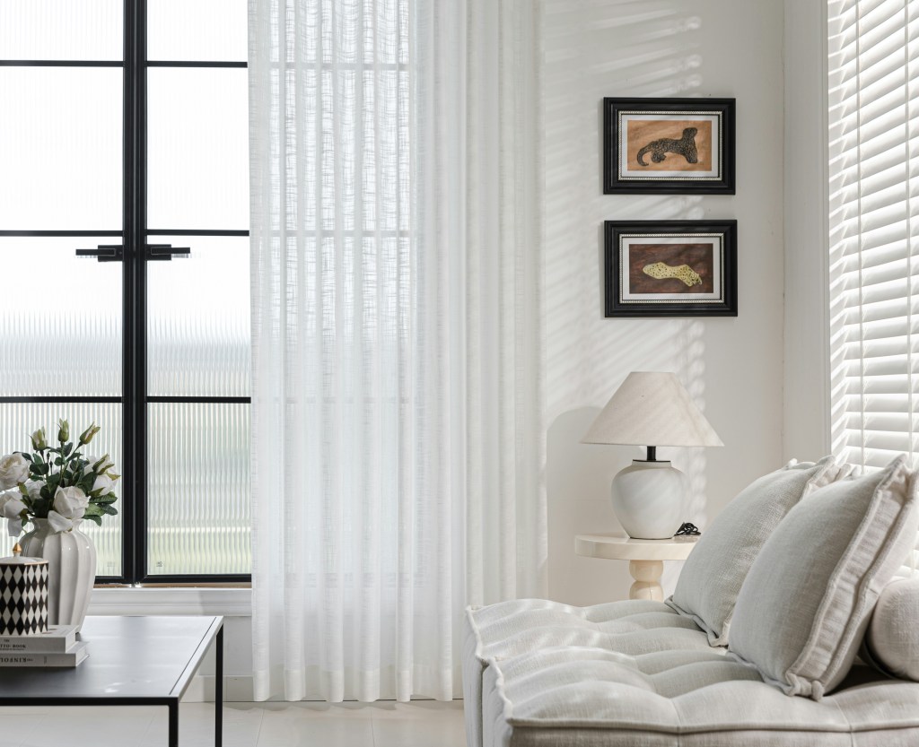 Bright minimalist living room with clean white decor, simple furniture, and uncluttered surfaces.