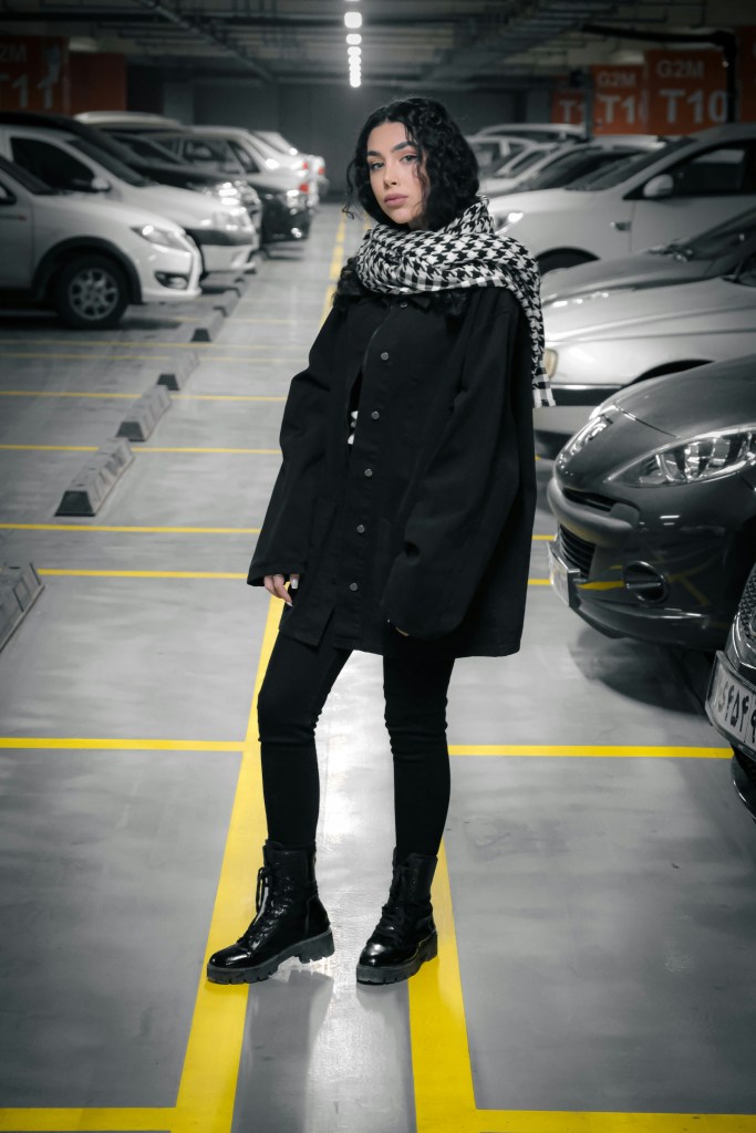 monochrome winter outfit in black with coat scarf and chunky boots in parking garage