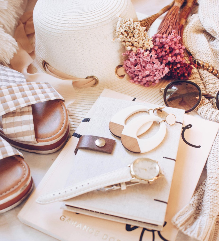 flat lay winter accessories including hat sunglasses earrings and watch on cozy background