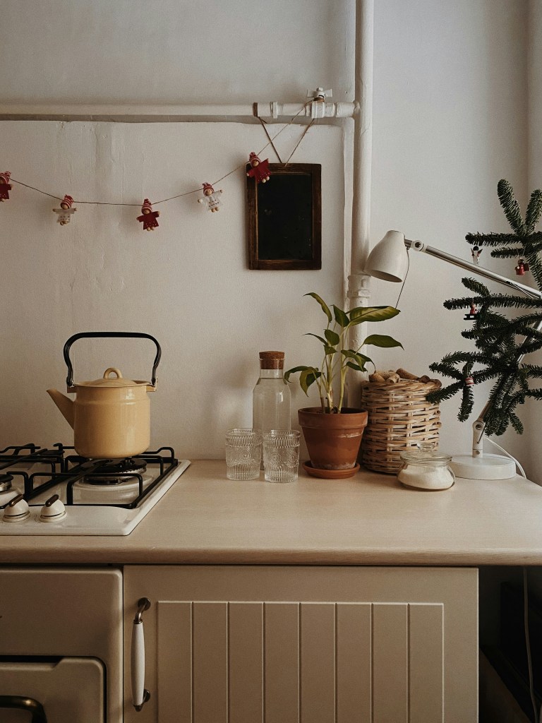 Minimal kitchen styled with small winter decor touches, plants, and warm neutral details.