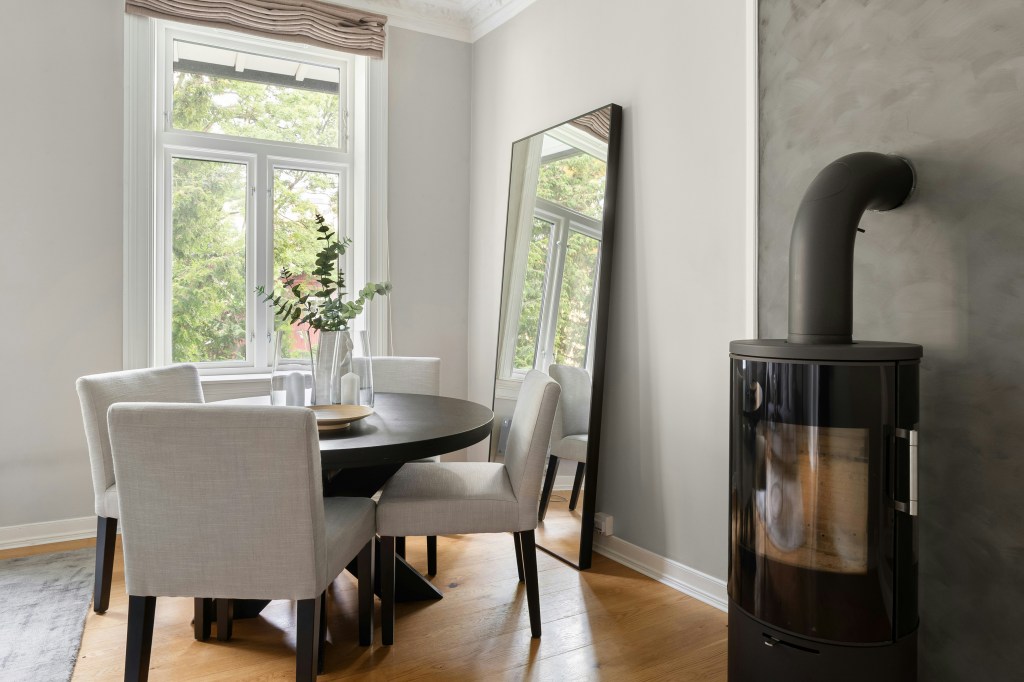 Minimal dining area styled for winter with warm wood flooring, neutral seating, and soft natural light.
