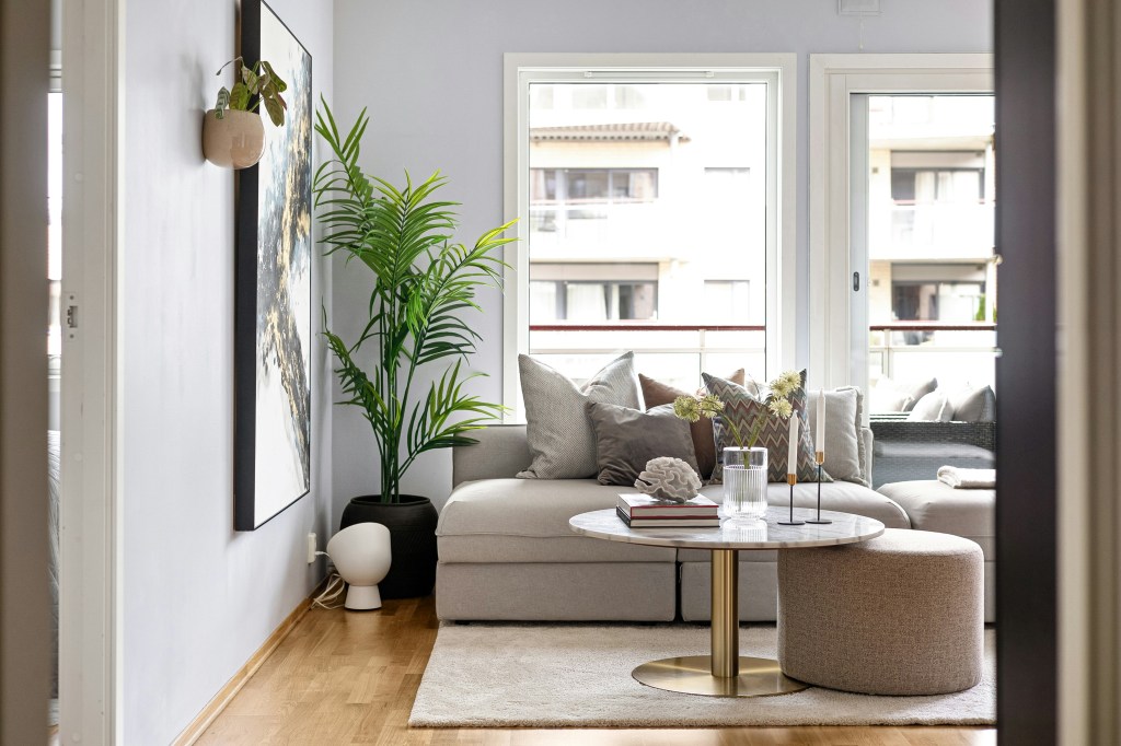 Soft neutral living room with a light beige sofa, indoor plants, natural light, and cozy minimalist décor.
