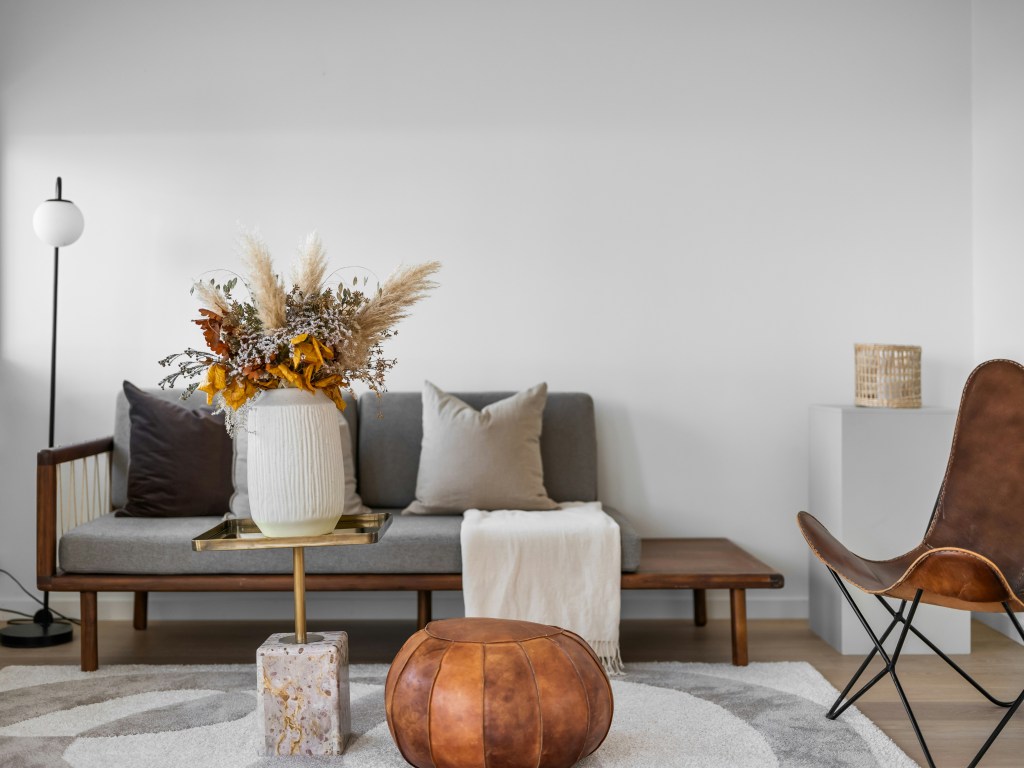 Minimal living room with warm decor accents complementing a subtle moody wall aesthetic.
