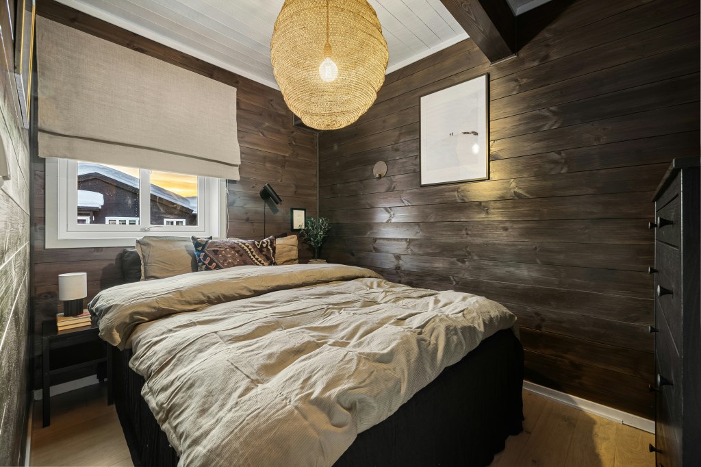 Cozy winter bedroom with layered bedding, warm wood walls, and soft ambient lighting.
