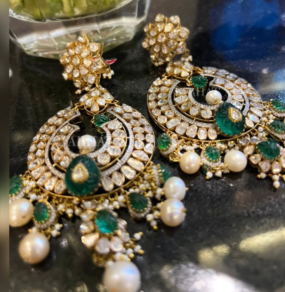 Kundan chandelier earrings with green stones and pearl drops.