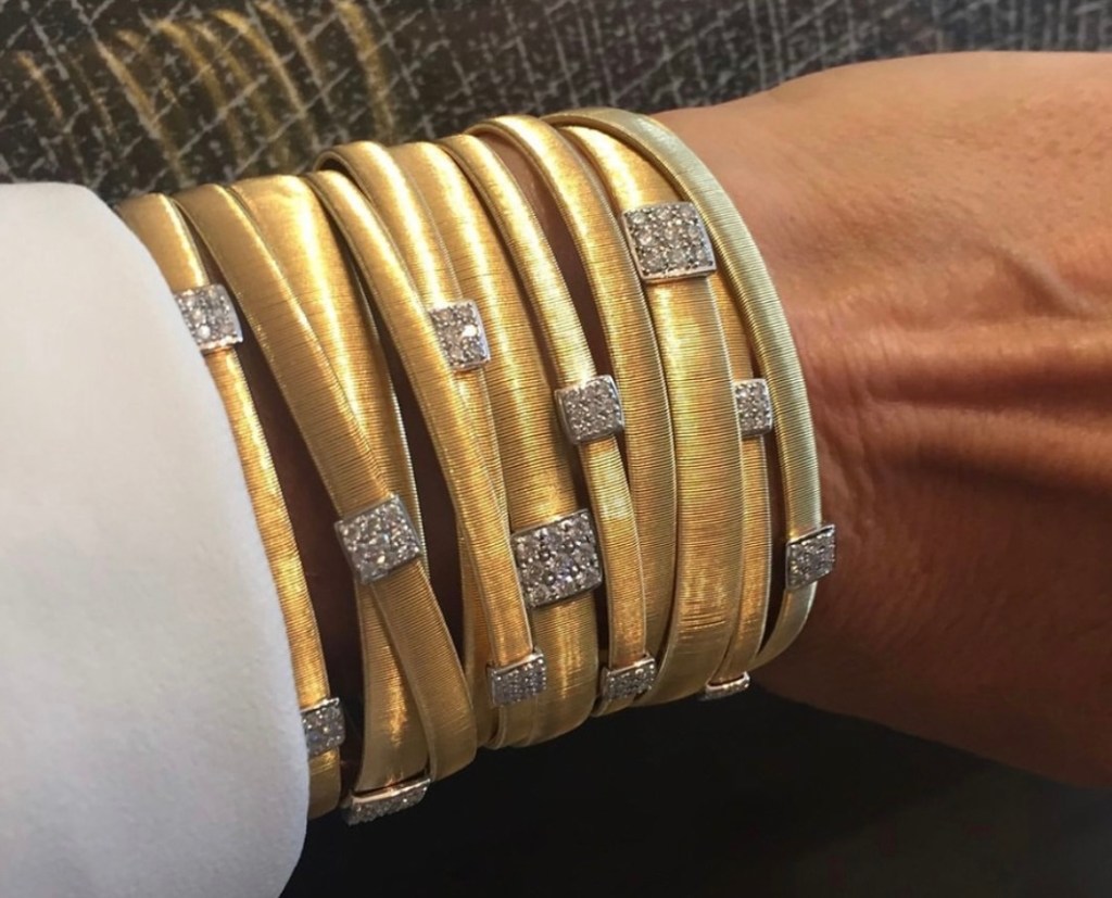 Stack of traditional gold bangles with embedded stone detailing.