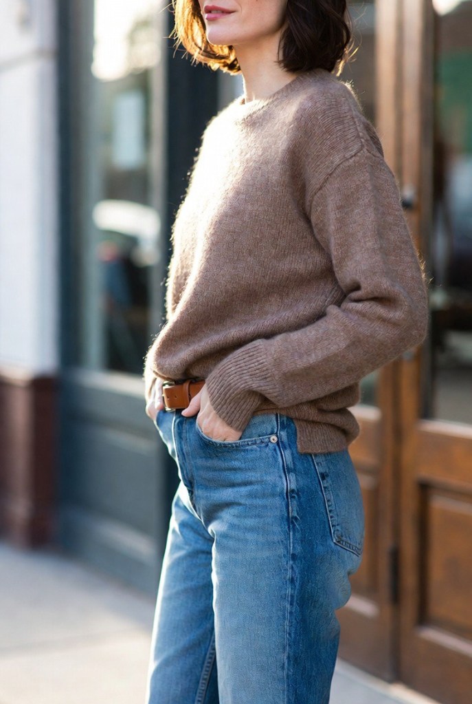 Close-up of a casual winter outfit with a knit sweater tucked into classic blue jeans